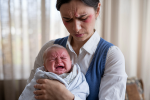 A tired mother holding a crying baby, representing the challenges of parenting.