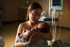 A cinematic shot of a new mother holding her baby in a hospital room, with tears in her eyes and a warm hue lighting the scene.